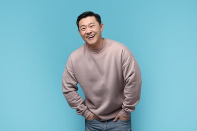 Portrait of happy man laughing on light blue background