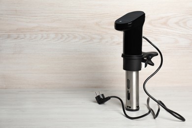Thermal immersion circulator on white wooden table, space for text. Sous vide cooker