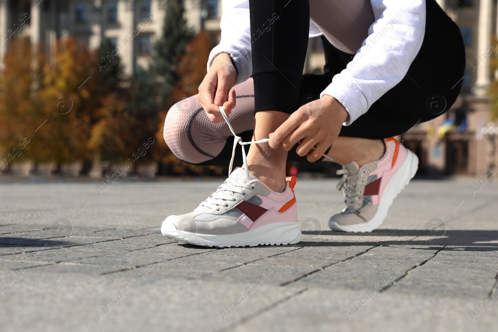 Photo of Sporty woman tying shoelaces before running outdoors