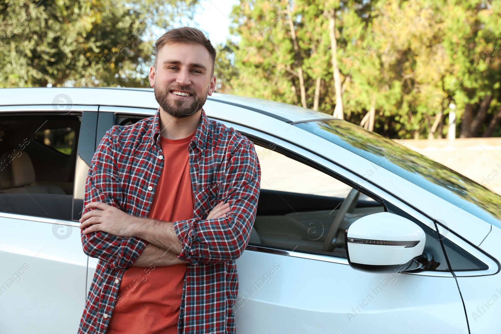 Photo of Handsome young driver near modern car on city street