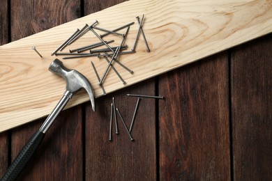 Photo of Hammer, plank and metal nails on wooden table, flat lay. Space for text
