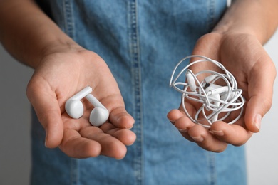 Photo of Woman holding different earphones on light background, closeup