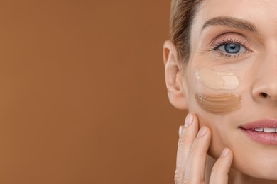 Photo of Woman with swatches of foundation on face against brown background, closeup. Space for text