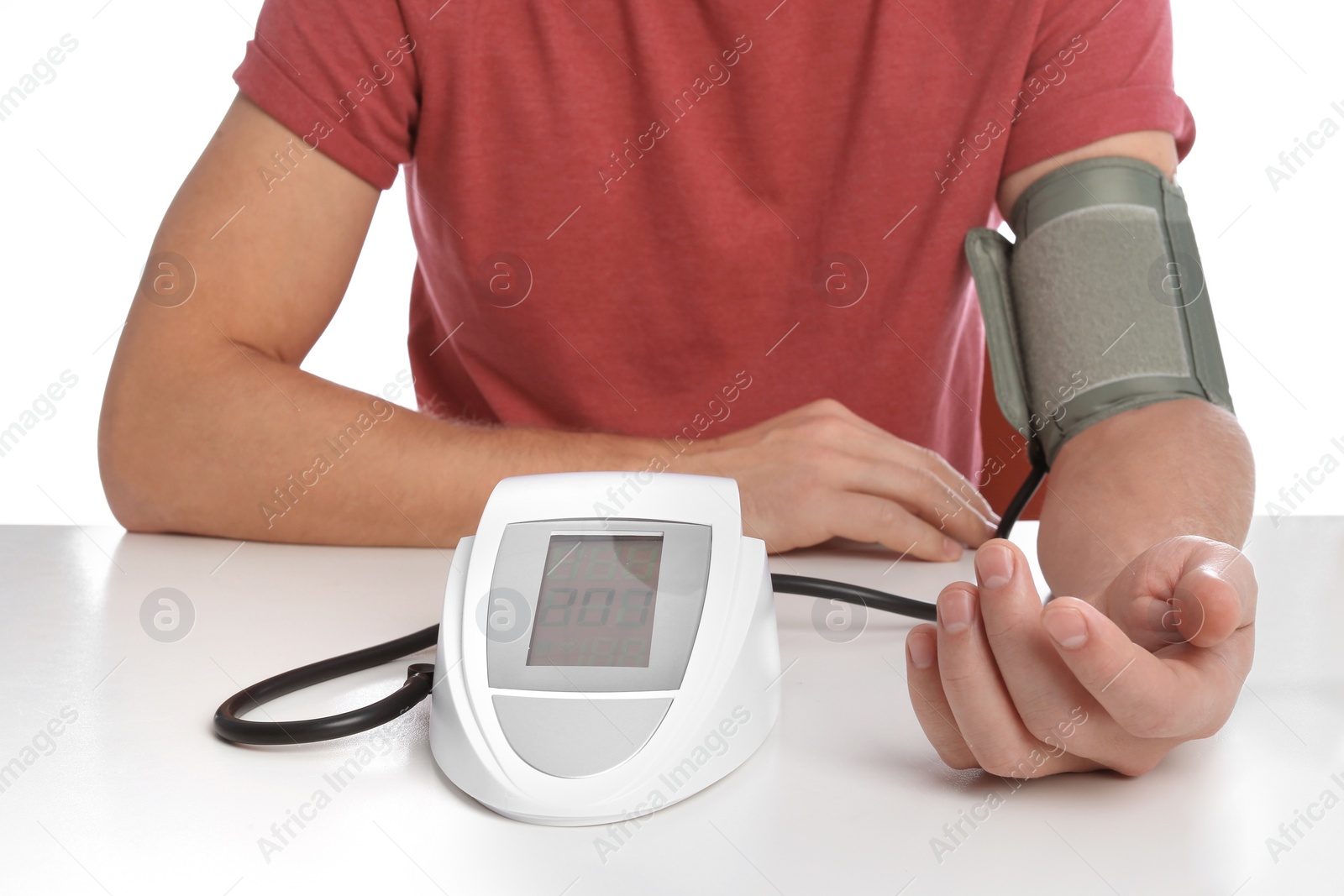 Photo of Man checking blood pressure with sphygmomanometer at table against white background, closeup. Cardiology concept