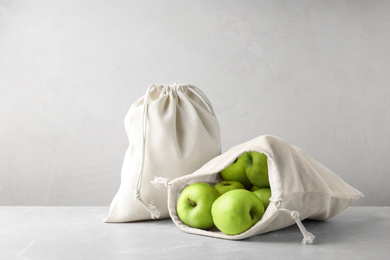 Photo of Cotton eco bags with apples on marble table