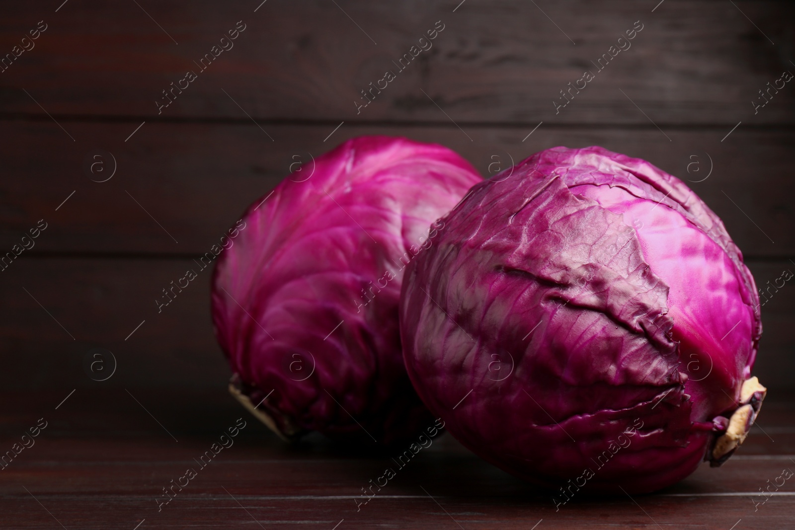 Photo of Fresh ripe red cabbages on wooden table. Space for text