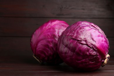 Photo of Fresh ripe red cabbages on wooden table. Space for text