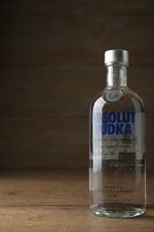 Photo of MYKOLAIV, UKRAINE - OCTOBER 03, 2019: Bottle of Absolut vodka on table against wooden background. Space for text