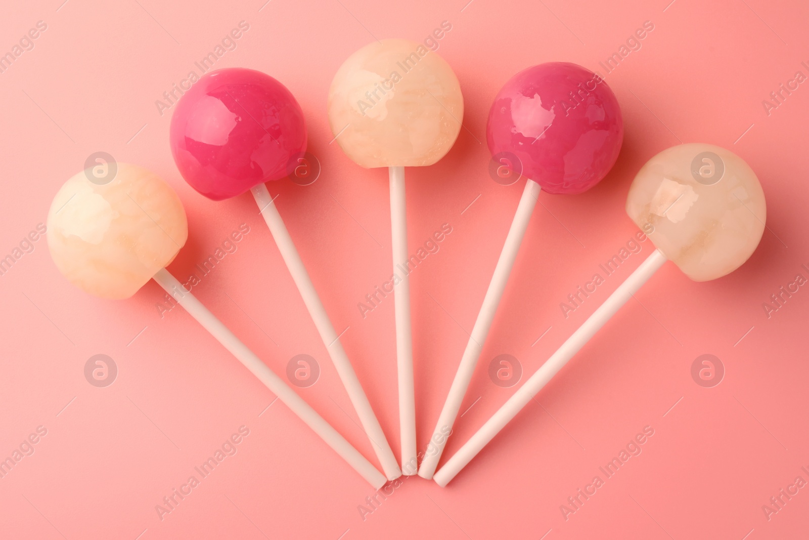 Photo of Tasty lollipops on pink background, flat lay