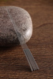 Photo of Acupuncture needles and spa stone on wooden table