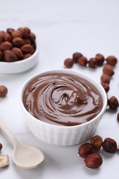 Bowl with chocolate paste and nuts on white marble table