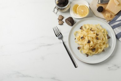 Delicious pasta with truffle slices served on white table, flat lay. Space for text