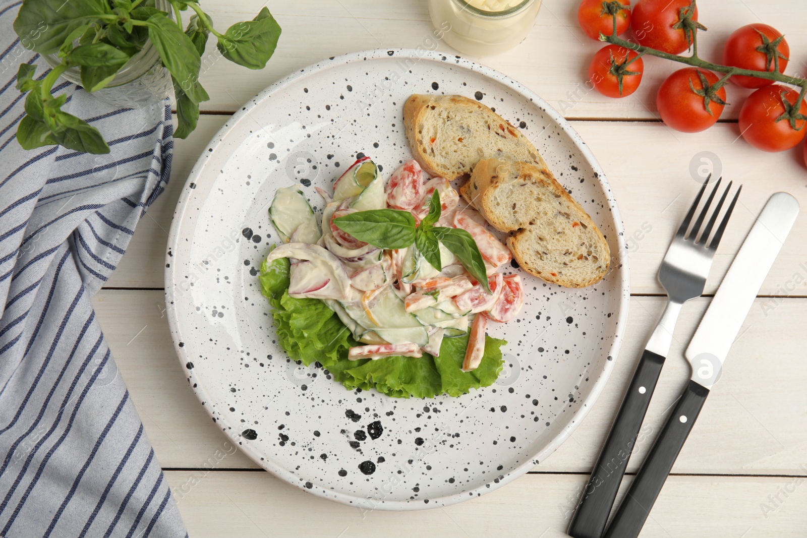 Photo of Plate of delicious vegetable salad dressed with mayonnaise and croutons served on white wooden table, flat lay