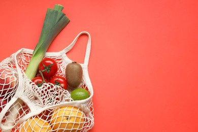 String bag with different vegetables and fruits on red background, top view. Space for text