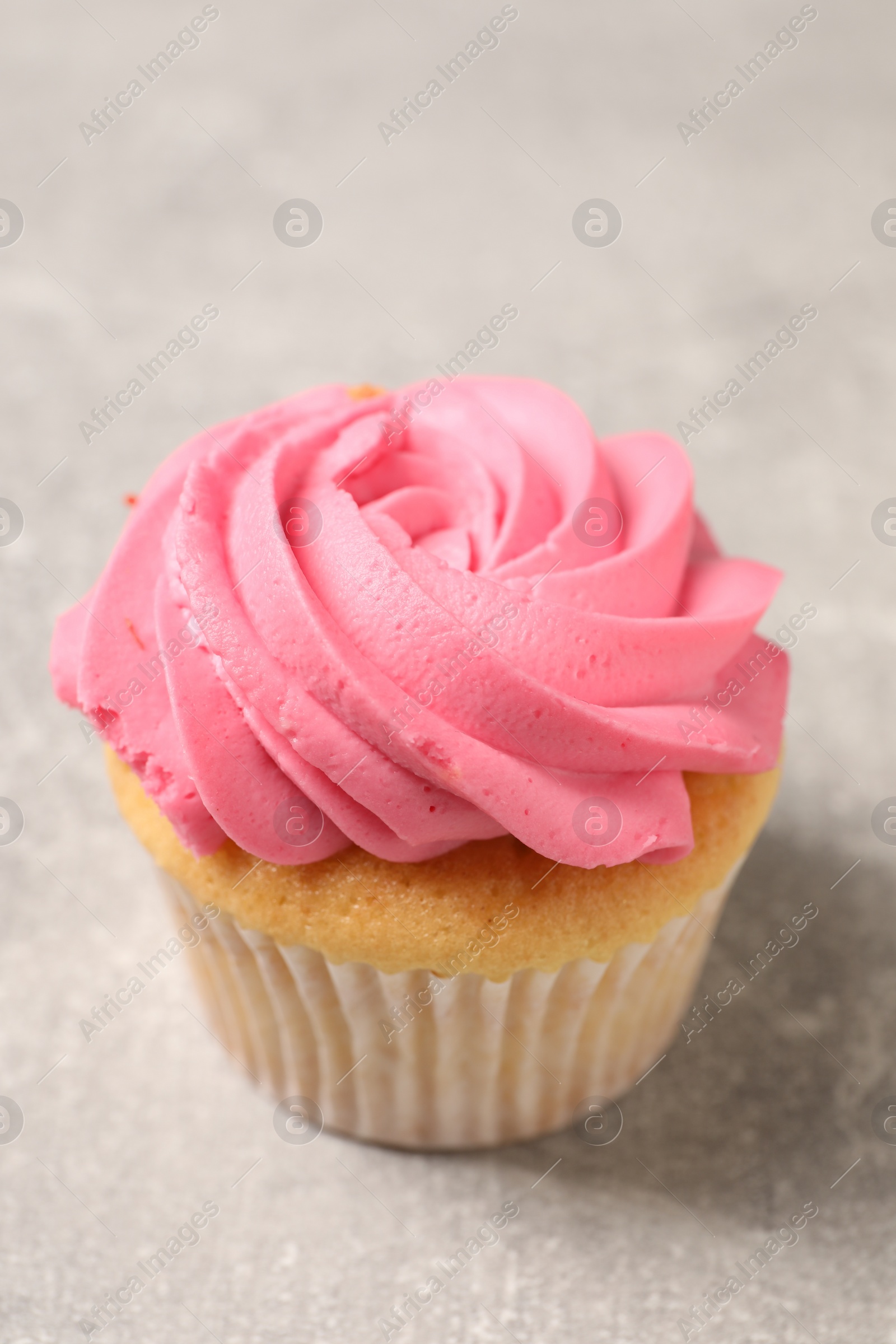 Photo of Delicious cupcake with bright cream on gray table