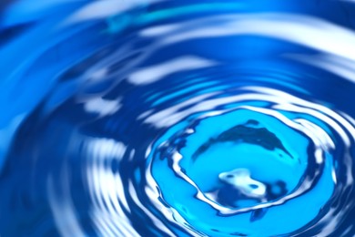 Photo of Splash of clear water on blue background, closeup