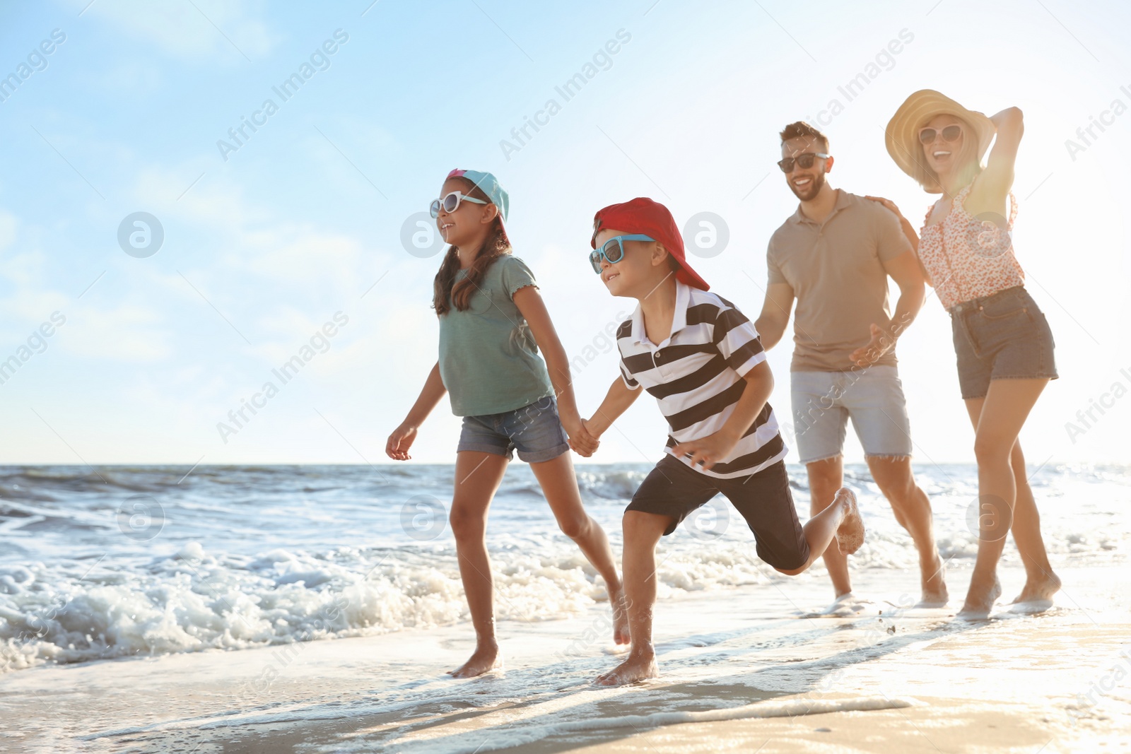 Photo of Happy family running on sandy beach near sea