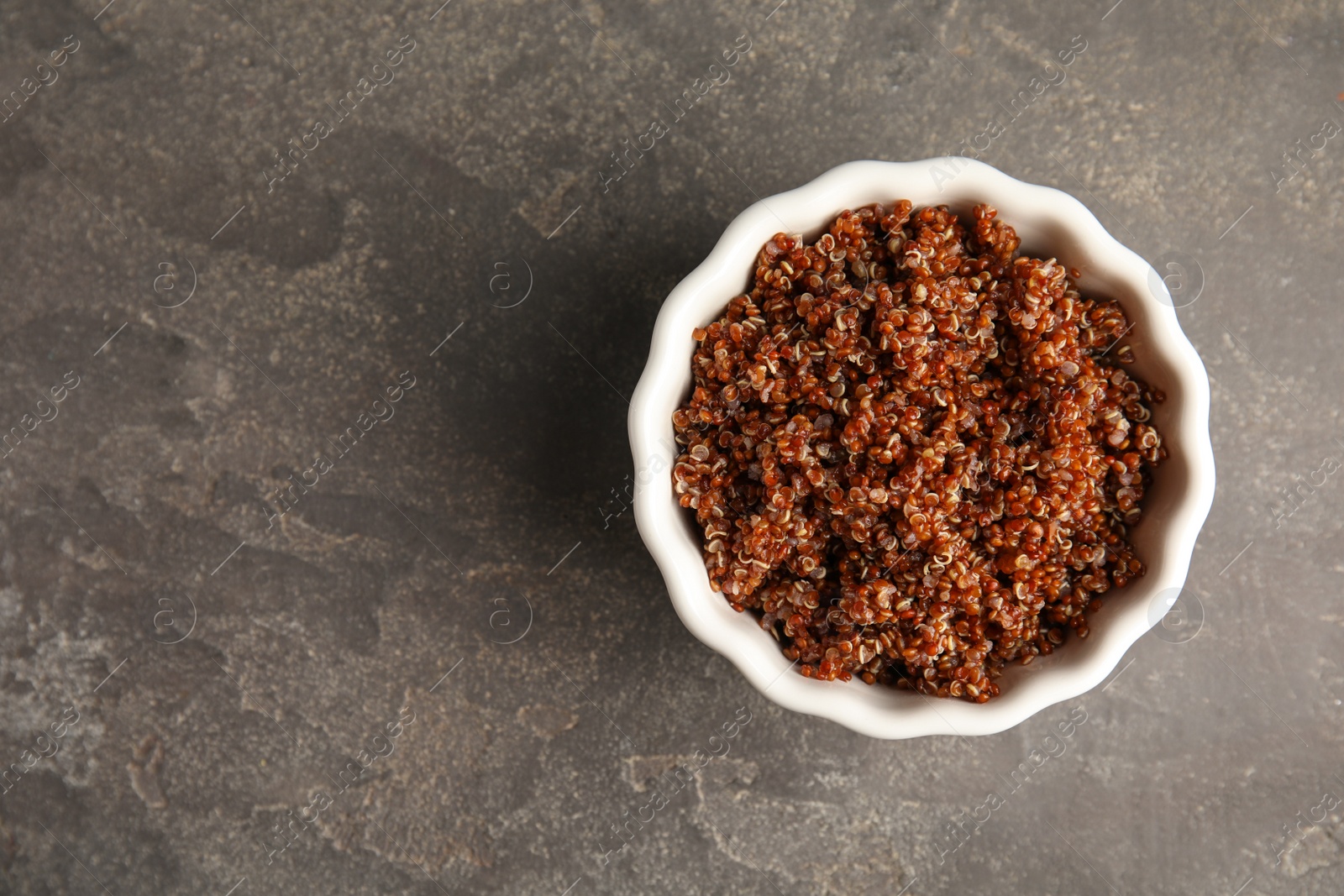 Photo of Cooked red quinoa in bowl on table, top view. Space for text