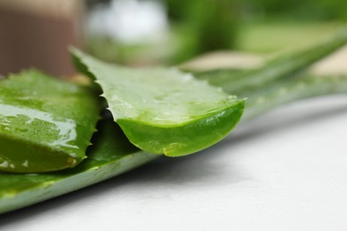 Fresh cut juicy aloe vera leaves on white table, closeup