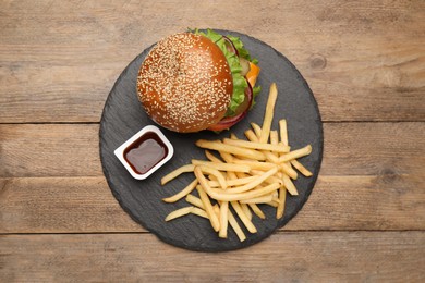 Burger, French fries and ketchup on wooden table, top view. Fast food