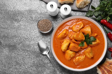 Photo of Bowl of delicious chicken curry on grey table, flat lay. Space for text