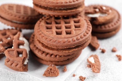 Tasty chocolate sandwich cookies with cream on light grey table, closeup