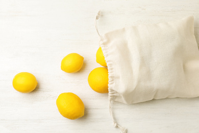 Cotton eco bag with lemons on white wooden background, flat lay