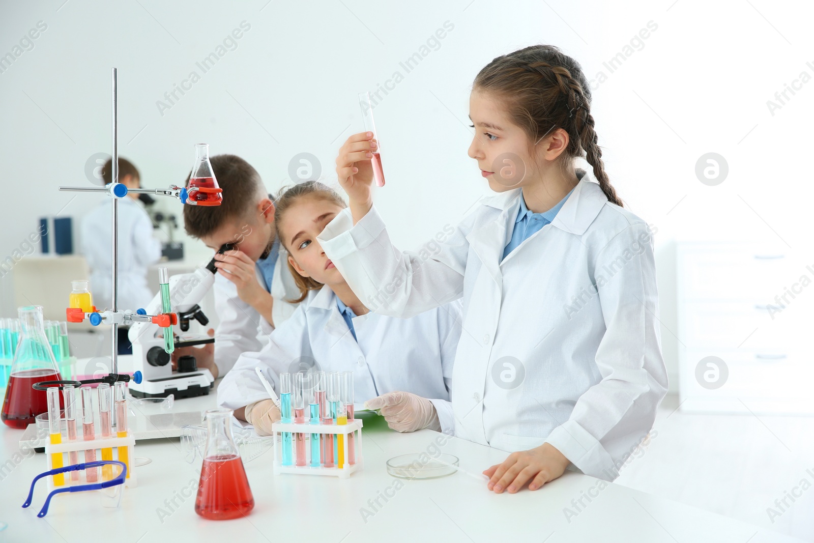 Photo of Smart pupils making experiment at table in chemistry class
