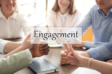 Image of Engagement concept. People showing thumbs up together at table, closeup