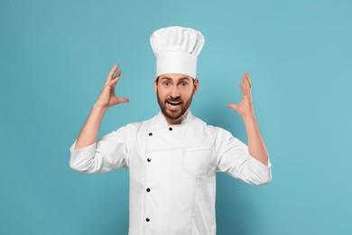 Photo of Emotional mature chef on light blue background