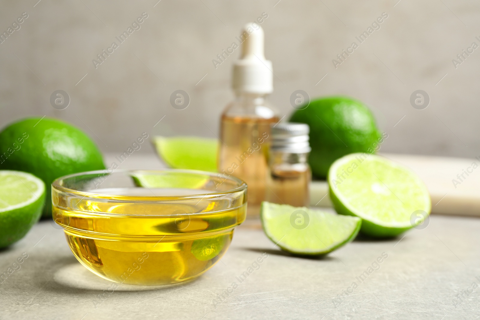 Photo of Lime essential oil and cut citrus fruits on light table