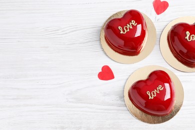 Photo of St. Valentine's Day. Delicious heart shaped cakes and confetti on white wooden table, flat lay. Space for text