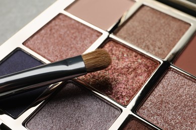 Photo of Beautiful eye shadow palette and brush on grey table, closeup