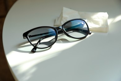 Photo of Stylish black eye glasses and cloth on white table. Space for text