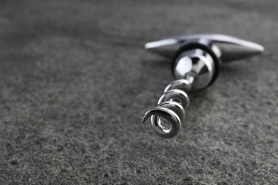 One metal corkscrew on grey textured table, closeup. Space for text