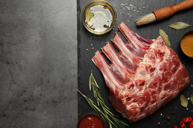 Raw ribs with herbs and spices on grey table, flat lay