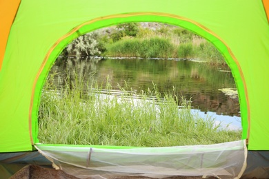 Green grass and picturesque pond, view from camping tent