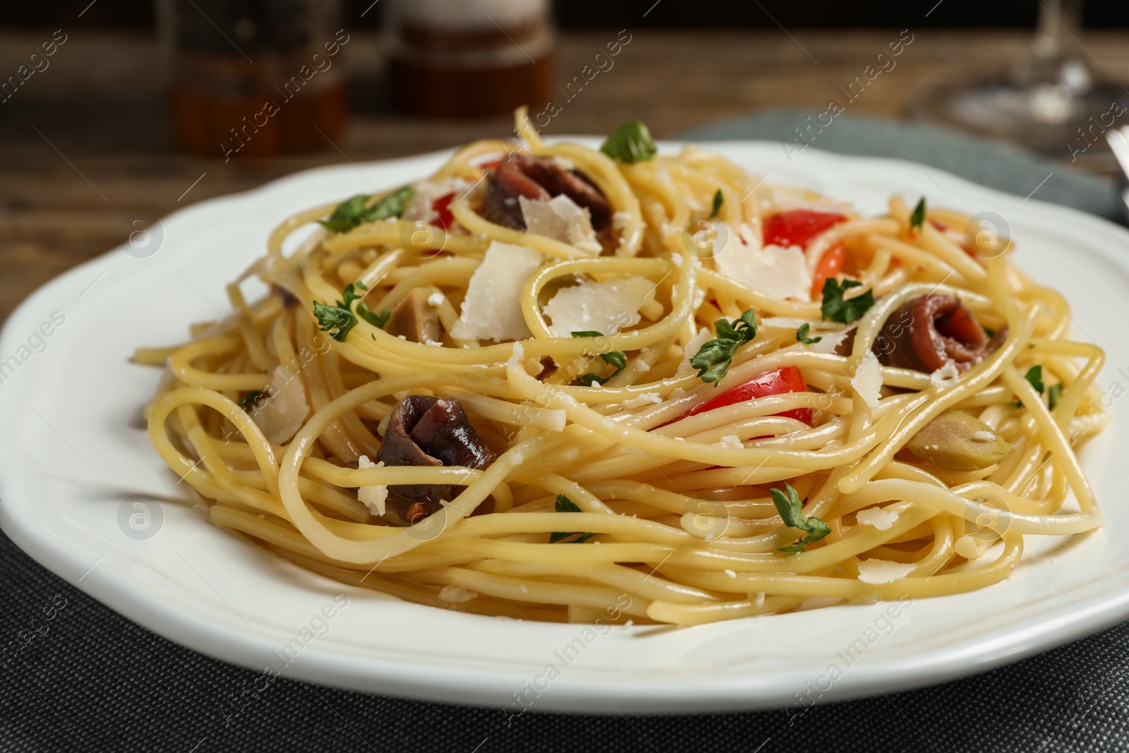 Photo of Delicious pasta with anchovies, tomatoes and parmesan cheese on table, closeup