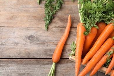 Crate of fresh carrots on wooden background, top view. Space for text