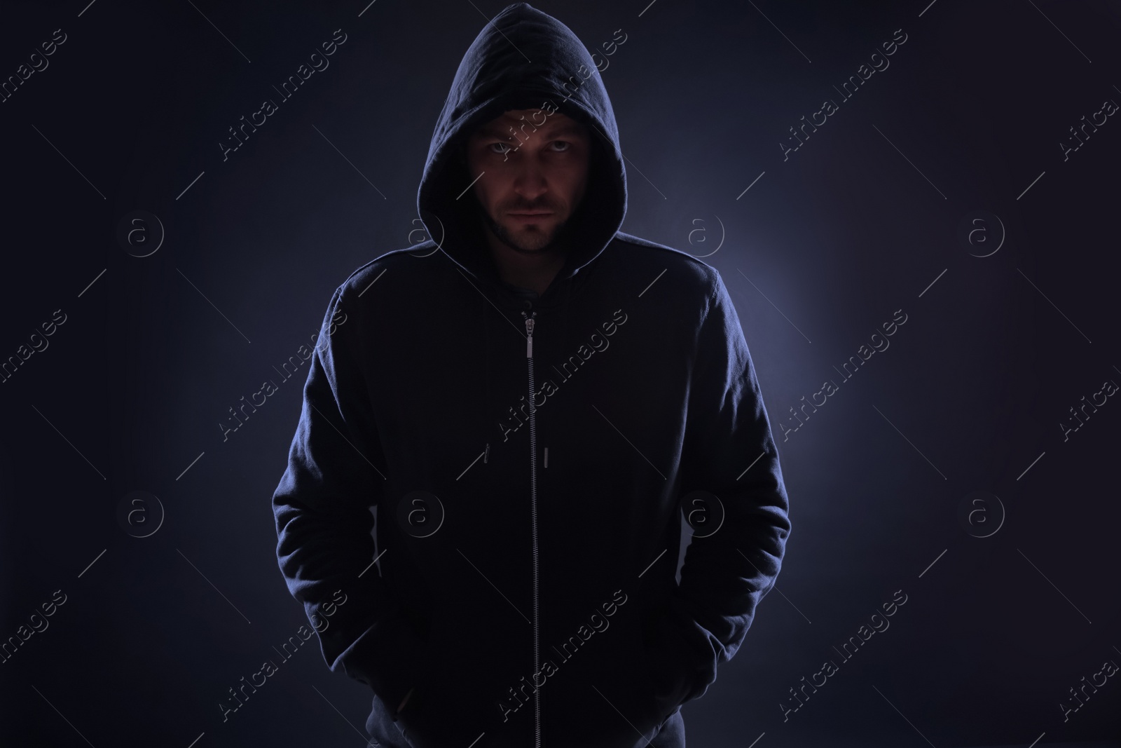 Photo of Mysterious man in hoodie on dark background. Dangerous criminal