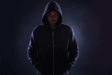 Photo of Mysterious man in hoodie on dark background. Dangerous criminal