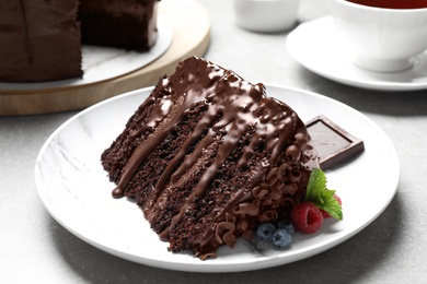 Photo of Piece of delicious chocolate cake decorated with fresh berries served on white table