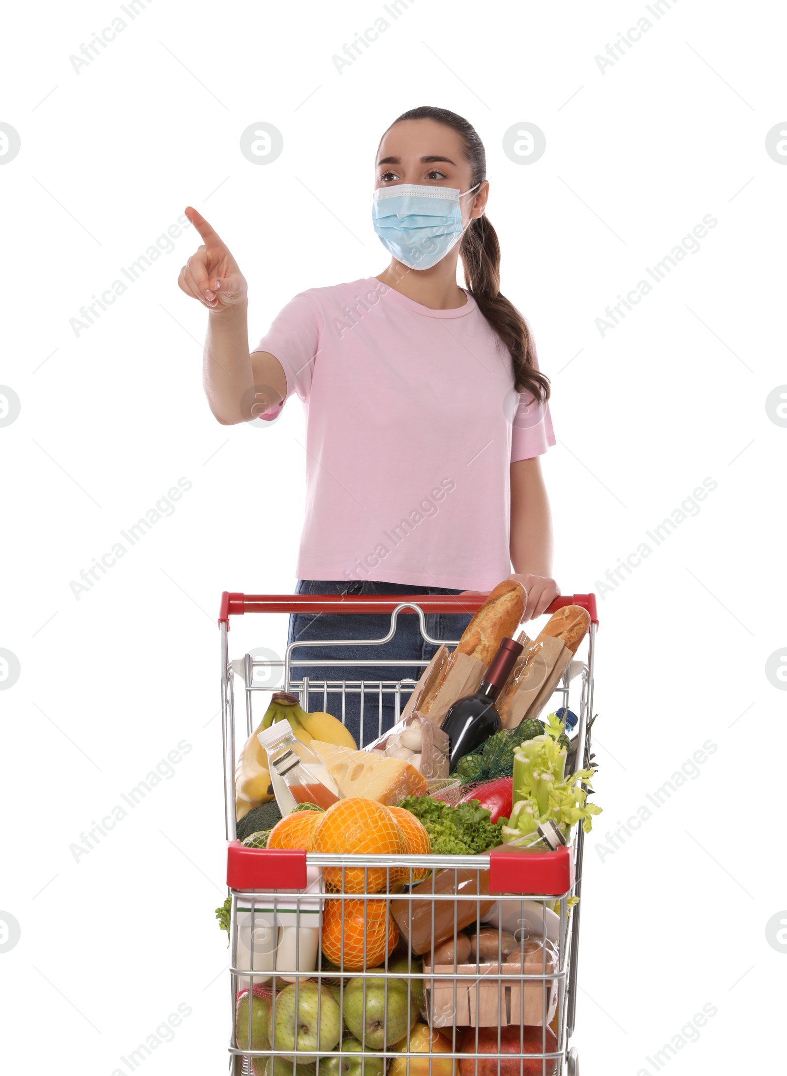 Photo of Woman with protective mask and shopping cart full of groceries on white background