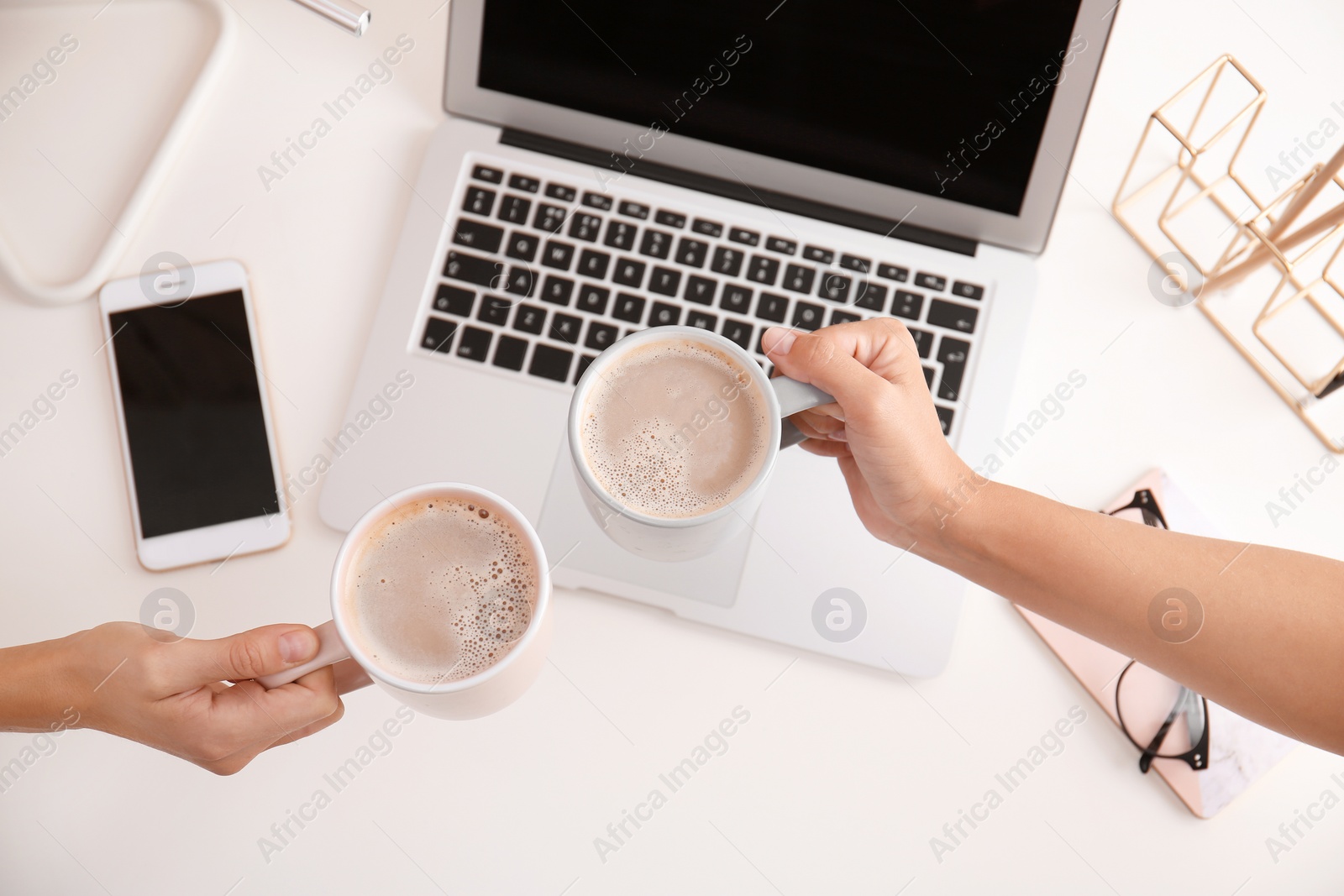 Photo of Women holding coffee cups at modern workplace in office, top view
