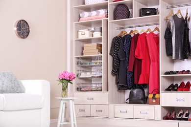 Photo of Modern wardrobe with stylish clothes in room interior