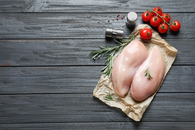 Flat lay composition with raw chicken breasts and ingredients on wooden background. Space for text