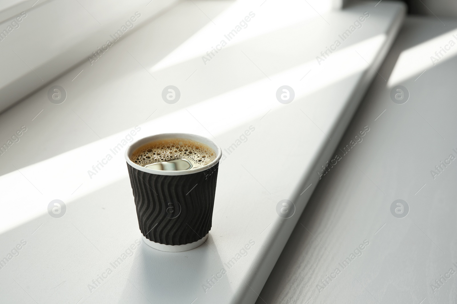 Photo of Cardboard cup of coffee on window sill indoors