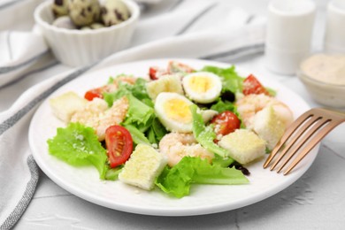 Photo of Delicious Caesar salad with shrimps and fork served on white table, closeup