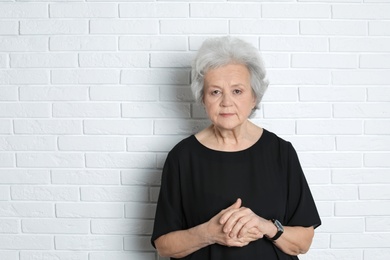 Portrait of mature woman near brick wall. Space for text