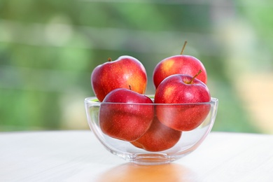 Bowl of fresh red apples on table indoors